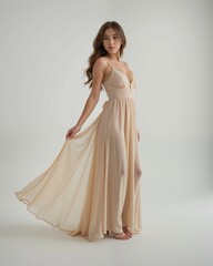 Elegant woman in flowy gown posing gracefully in soft lighting