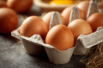 A carton of eggs with one egg in the middle. The carton is full of eggs and the egg in the middle is the only one that is not fully covered by the carton