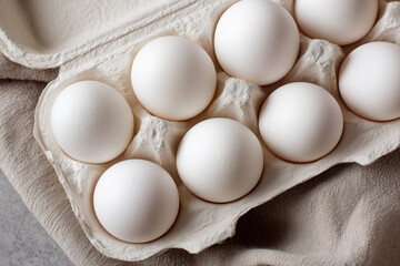 A carton of eggs with six eggs in it. The eggs are white and are sitting in a carton
