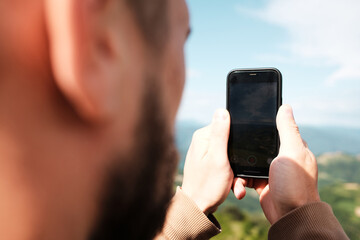 Close-up of a phone screen as a man records a scenic mountain view in Serbia on a spring day. Rear close view