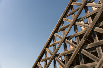 Close-up of abstract wooden framework with diagonal beams creating geometric patterns, set against...