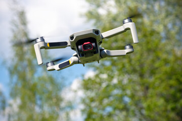 Small Flying Qunmanned aerial vehicle in flight mode with camera outdoor on sunny day summer time...