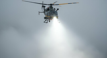 Grey Helicopter Flying with Bright Spotlight in Cloudy Sky