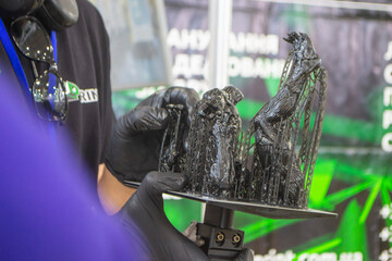 An object printed on a 3D printer from hardened rubber close-up. Model black color created on a 3D printer from hardened rubber under influence of ultraviolet light. SLA 3D printing. Stereolithography