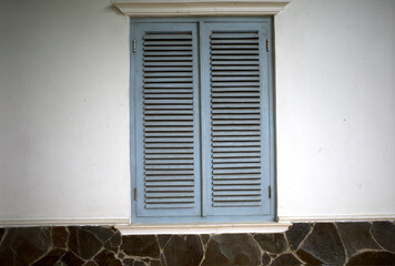 A weathered light blue old vintage window on white wall