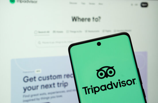Dhaka, Bangladesh- 22 June 2025:  The logo of the Tripadvisor is displayed on a smartphone screen, and the website tripadvisor is visible on a computer screen in the background.