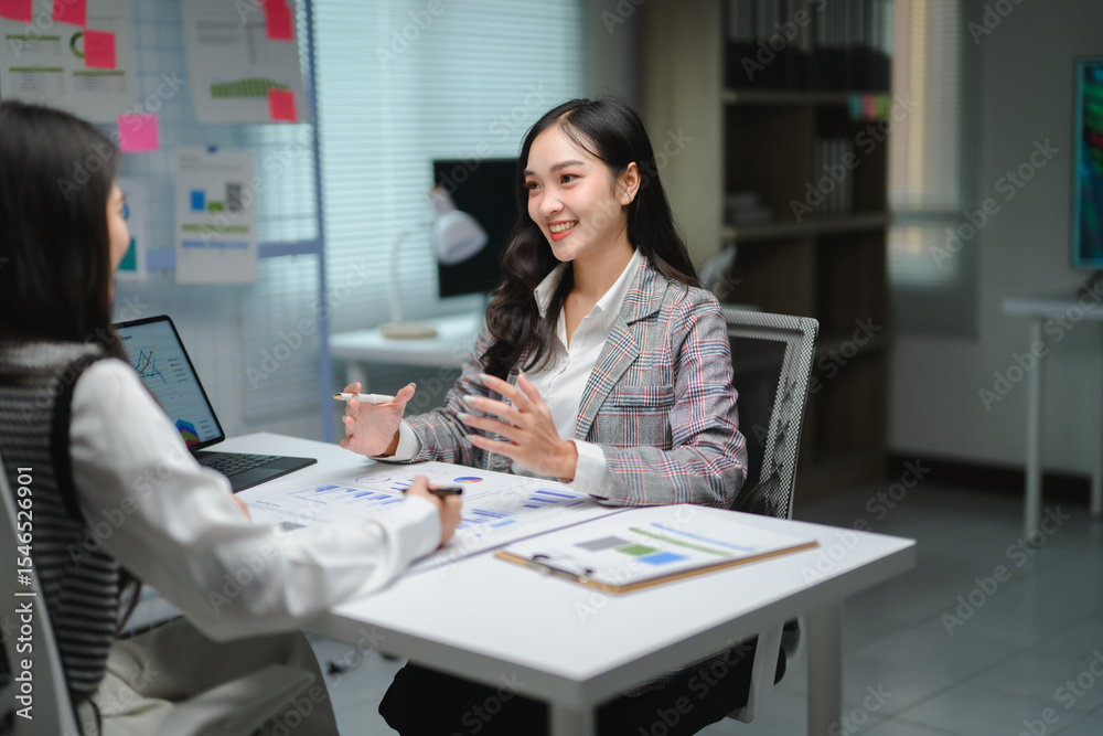 Poster businesswomen are using data charts and graphs to analyze and discuss marketing strategy together in