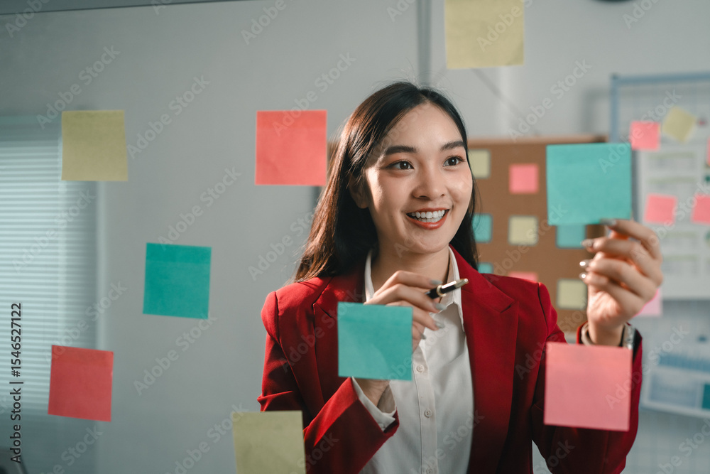 Poster asian businesswoman using colorful sticky notes to share ideas with colleagues during a brainstormin