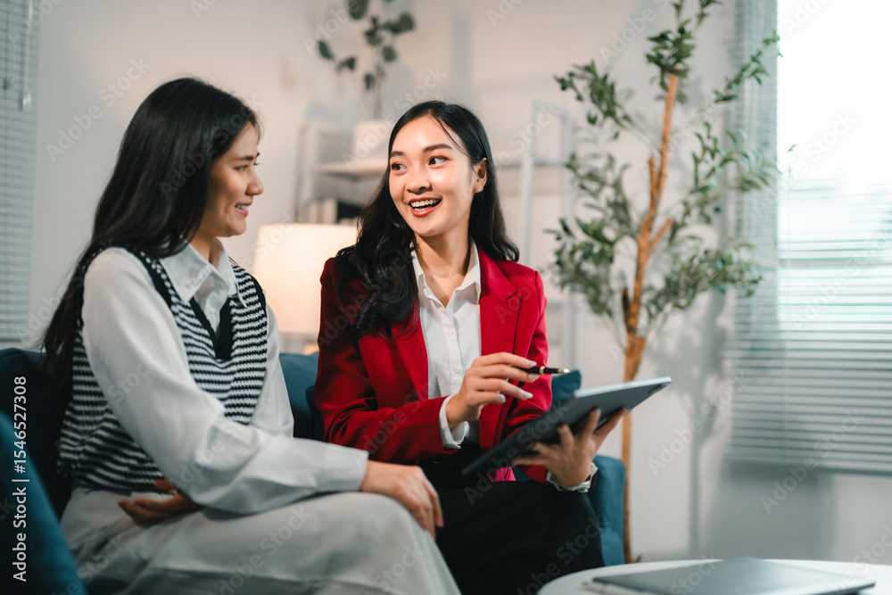 Poster two businesswomen discussing working using tablet and smiling in modern office