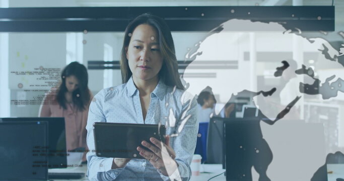 Holding digital tablet middle-aged woman analyzing data at open-plan office, with computer monitors