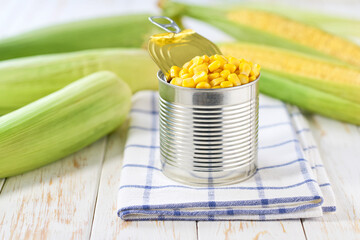 Canned young corn grain on a light kitchen table, selective focus.