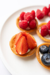 Tartlets with fresh berries on a white background. Selective focus.