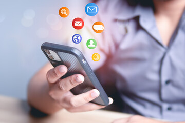 Hand holding a smartphone with floating application icons around it, connectivity to the digital world, online communication, technology, social media, digital marketing and modern lifestyle.