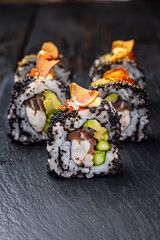 Sushi roll with salmon, avocado and cucumber on a black background