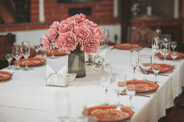 Elegant dining setup featuring vibrant pink flowers and meticulously arranged tableware, creating...
