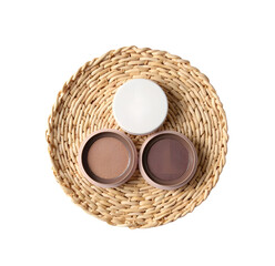 Three Round Eyeshadow Compacts on Rattan Mat on White Background top view
