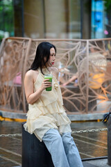 Elegant Woman Holding Matcha Green Tea with Wind Blown Hair Outdoors