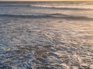 Landscape. The shoreline. Waves and ocean foam. Rocks. View from above. Texture background. Postcard. Poster.