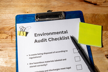 This scene features an environmental audit form and a pen placed on a wooden desk, representing...