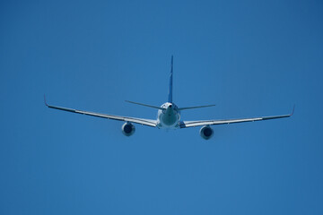 Airplane in the blue sky. An airplane moving away after takeoff