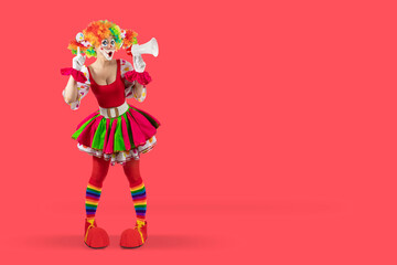 Funny female clown shouting with loudspeaker pointing finger up. Woman entertainer as colorful Joker, suit and wig, clown whiteface makeup. Professional actor at events