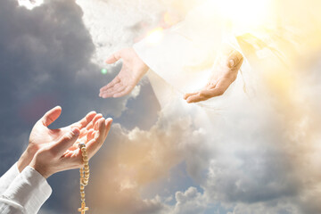 Praying hands with wooden rosary with cross against the sky. Lending Helping Hand is associated with the Savior Jesus Christ. Biblical scene, Holy Scriptures of Old, New Testaments, Christian religion