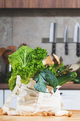 Fresh vegetables and herbs in eco-friendly bag on kitchen table ready for healthy meal preparation