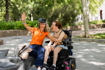 Woman using vr headset is sharing experience with her disabled friend in a park