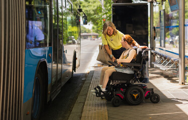 Naklejka na ściany i meble Woman helping disabled girl on wheelchair to board bus at bus stop