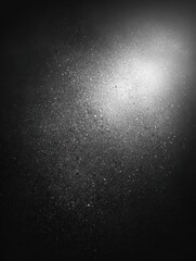 Obraz premium Black matte textured background with floating dust particles illuminated by soft light in the top right corner, creating a deep contrast between black and white. This abstract design emphasizes textu