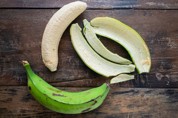 Green plantain being prepared for cooking patacones on rustic wooden table © Stock Latino
