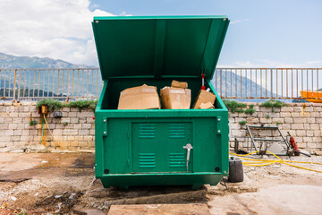 Green industrial dumpster filled with cardboard boxes outdoors. Waste management, recycling...