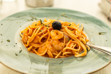Shrimp spaghetti with tomato sauce served on ceramic plate. Mediterranean cuisine, seafood lunch and Italian restaurant dining.