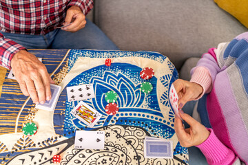 Senior couple playing cards and gambling with chips and dice at home