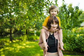 Obraz premium Cute big sister cuddling with her toddler brother. Adorable teenager girl hugging her small sibling. Children exploring nature.