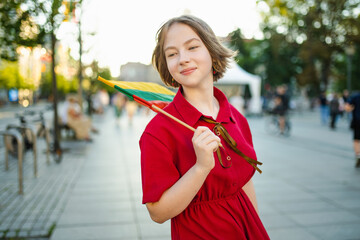 Cute young girl holding tricolor Lithuanian flag on Lithuanian Statehood Day.