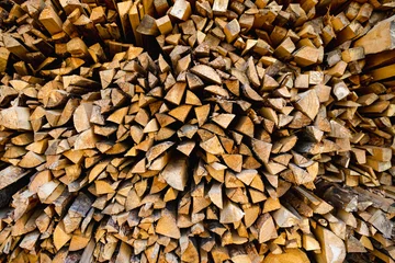 Fototapete Rund Tightly packed pile of split firewood arranged in an organic pattern, with earthy textures revealing freshly chopped surfaces of the wood, ready for seasoning use as fuel © MNStudio
