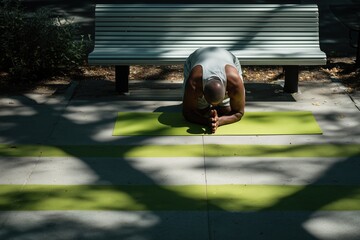 Man practicing crow pose on a lime green mat in a peaceful outdoor park setting surrounded by nature