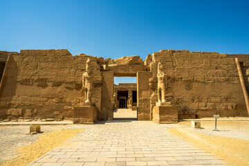 Ancient Egyptian temple entrance with carved statues and hieroglyphs at Ramses III temple complex...
