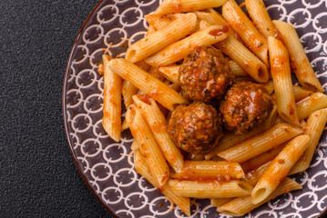 Penne pasta with meatballs in tomato sauce with salt and spices. Italian food penne pasta