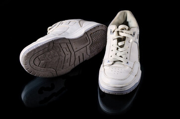 Used white casual shoes on black studio background