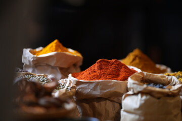 Colorful selection of dried herbs, spices, and natural ingredients in paper bags on rustic market...