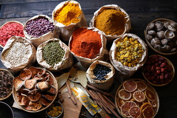 Colorful selection of dried herbs, spices, and natural ingredients in paper bags on rustic market table. Traditional Asian and herbal medicine concept.