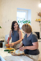Two women of different generations cooking together in a cozy kitchen. mother and daughter cooking...