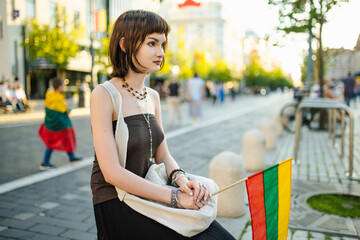 Cute young girl holding tricolor Lithuanian flag on Lithuanian Statehood Day.