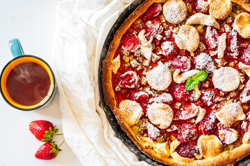 Rhubarb tart with strawberries and sugar on a white table. Traditional French dessert. Top view.