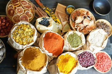 Colorful selection of dried herbs, spices, and natural ingredients in paper bags on rustic market...