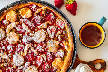 Rhubarb tart with strawberries and sugar on a white table. Traditional French dessert. Top view.