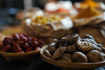 Colorful selection of dried herbs, spices, and natural ingredients in paper bags on rustic market table. Traditional Asian and herbal medicine concept.