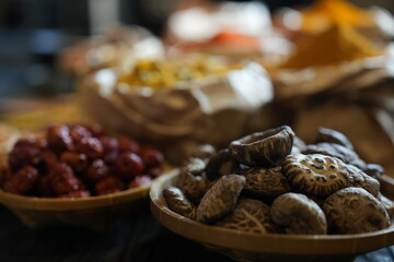 Colorful selection of dried herbs, spices, and natural ingredients in paper bags on rustic market table. Traditional Asian and herbal medicine concept.
